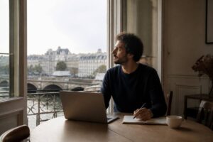Persoon gebruikt een laptop en notitieboekje om vakanties te vergelijken